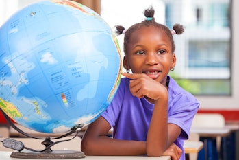 African girl at school with earth globe in background, geography and education concept.