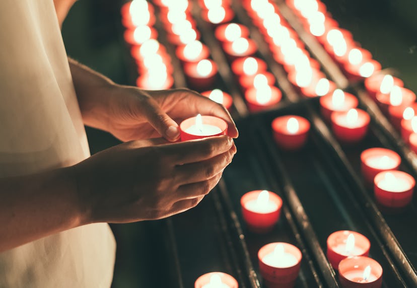 Woman holding candle near altar in church.