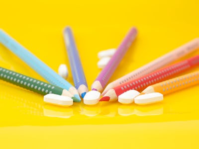 Medication for children concept. Color pencils and drugs on yellow background 