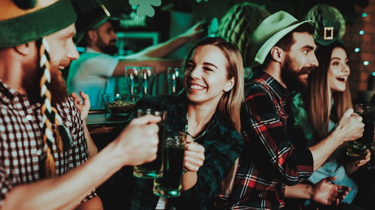 A group of friends hangs out in a bar on St. Patrick's Day, and wears flannels and green attire.