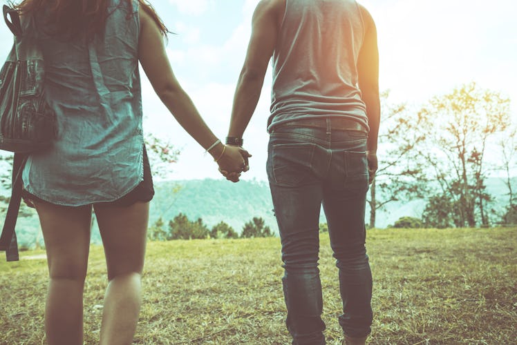 Both women and men are walking hand. On a natural grass mountain