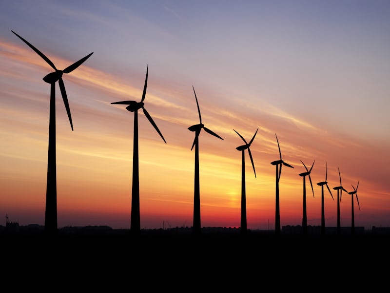Wind turbines farm at beautiful orange sunset.