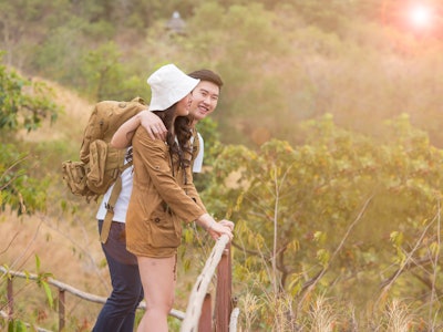 Young Asian couple, newly weds or lovers exploring forest, green naature. Tourist, backpack adventur...