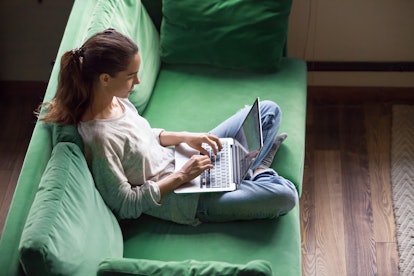 Relaxed woman using laptop sitting on sofa, millennial girl checking news in social networks, chatti...