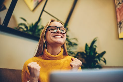 Happy female freelancer feeling excited of completed program project on laptop computer connected to...