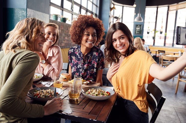 Four girls pose at a table at a restaurant for a selfie.