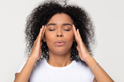 Nervous african woman breathing calming down relieving headache or managing stress, black girl feeli...