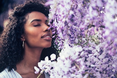Thoughtful happy young black woman surrounded by flowers