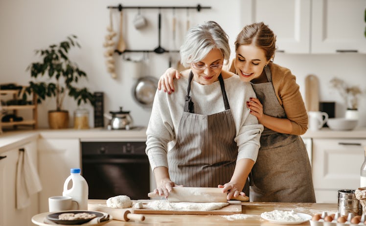 A happy mother and daughter bake together in the kitchen.