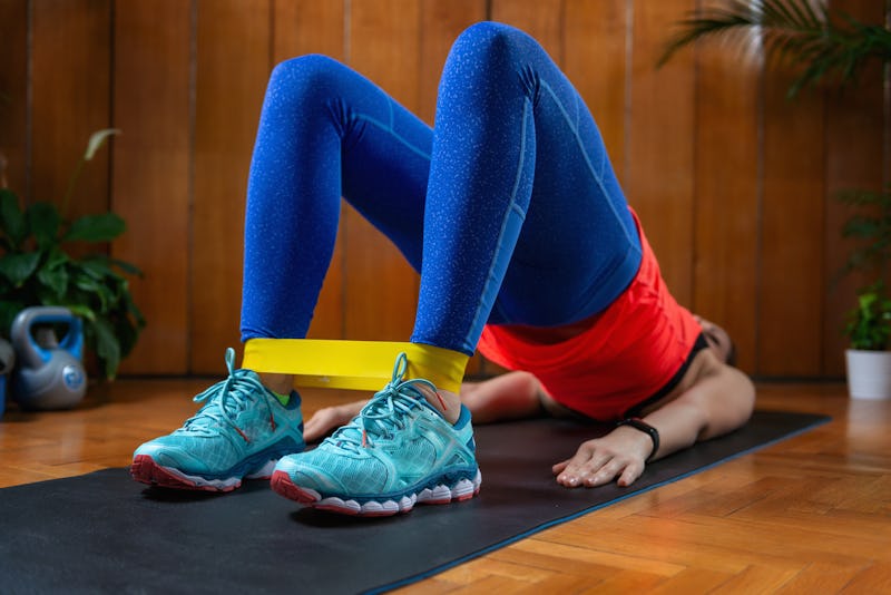 Woman exercising with rubber resistance band at home