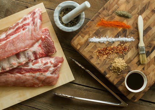 Horizontal photo of a three full rack of Raw Ribs with mortar and pestle, bbq sauce Baste, Herbs and...