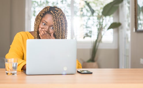 African american woman with laptop cover mouth with hand shocked with shame for mistake, expression ...