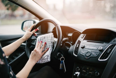 Woman cleaning car steering wheel. Modern car interior