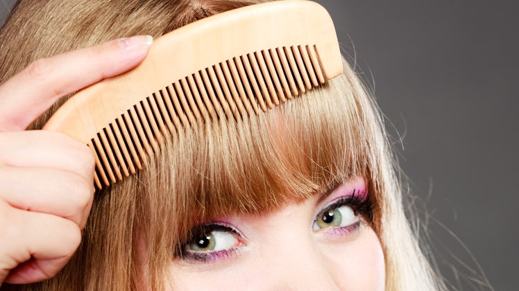 Fashion beauty and haircare concept. Closeup young woman refreshing her hairstyle girl combing her h...