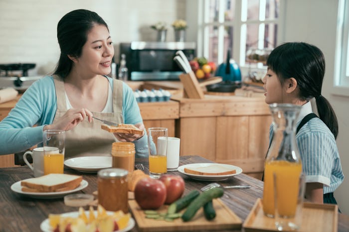 Table set for tasty family breakfast with toast butter peanut jam. happy sweet mom and kid sitting a...