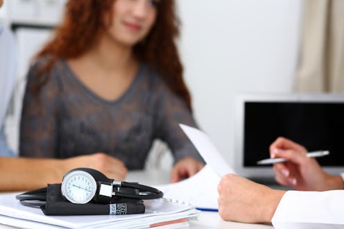 Medical manometer lying on table while doctor consult young couple patients closeup. Motherhood and ...