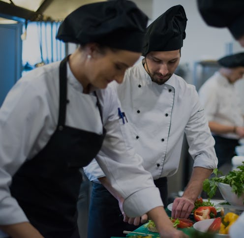 Professional team cooks and chefs preparing meals at busy hotel or restaurant kitchen