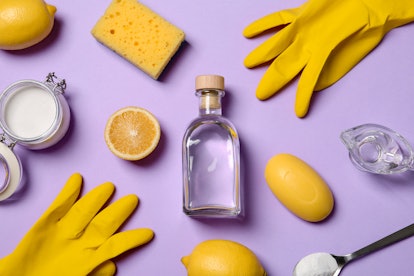 Flat lay composition with vinegar and cleaning supplies on color background
