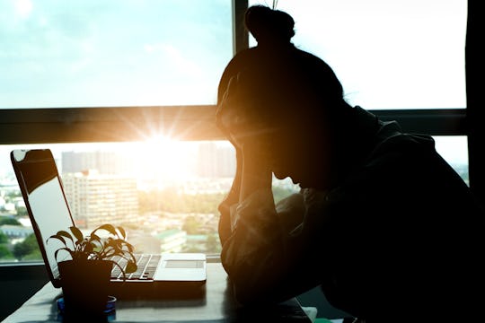 women working at laptop with head in hands