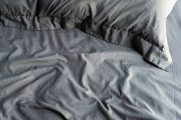 Empty messy dark gray bed with pillows 