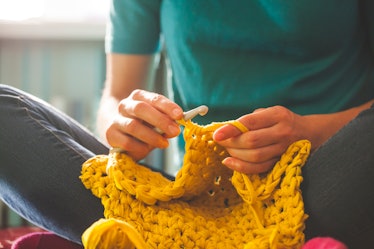 Woman knits crochet. The girl sits on the couch and knits from knitting yarn. Crochet thick threads....