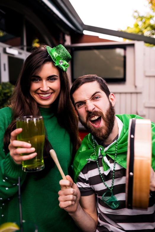 A young couple hangs out in a bar on St. Patrick's Day and drinks green beer.
