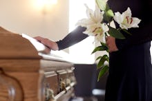 people and mourning concept - woman with white lily flowers and coffin at funeral in church