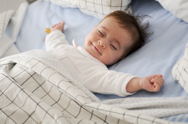 Smiling baby girl lying on a bed sleeping on blue sheets, Pisces baby your pisces child