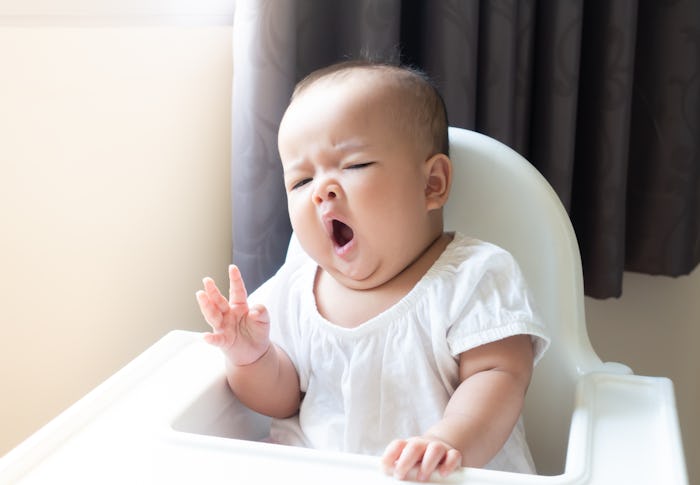 Asian baby girl sitting and yawning on  white high chair