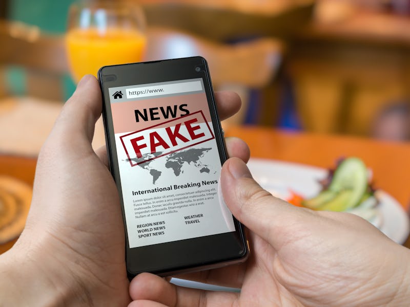 Man is holding smartphone and reading fake news on internet. Propaganda, disinformation and hoax con...