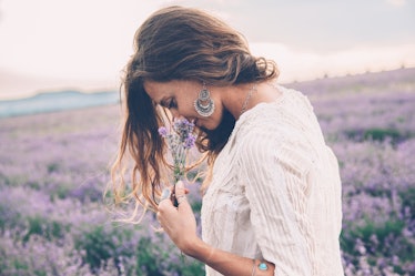 Beautiful model walking in spring or summer lavender field in sunrise backlit. Boho style clothing a...
