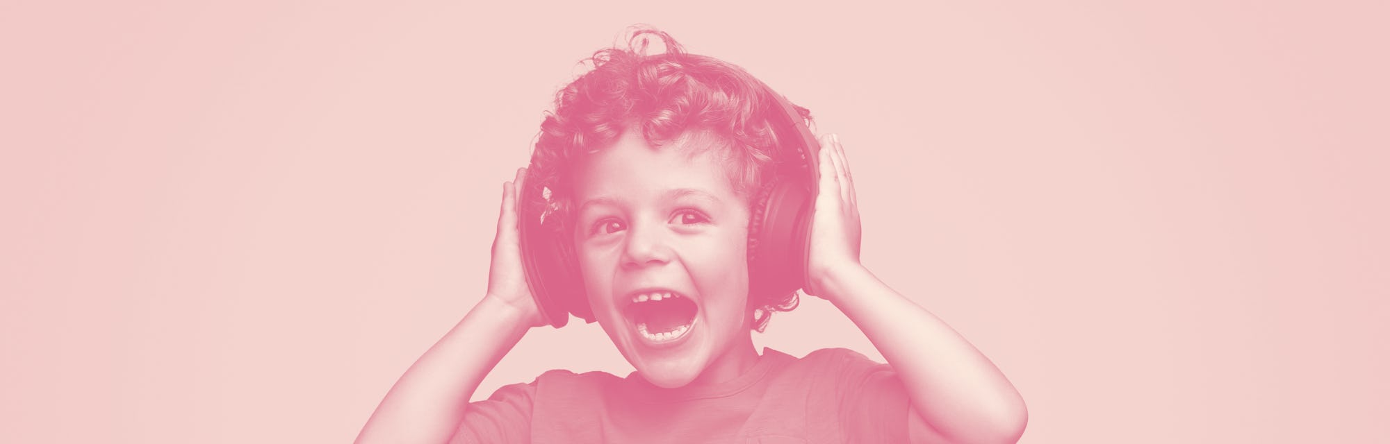 Screaming excited curly kid in headphones listening to music on blue background