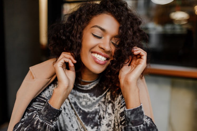 Close up lifestyle portrait of happy carefree black woman enjoying coffee break in Paris. Wearing el...