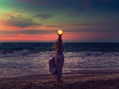 The girl holds the moon in her hands. Beautiful sunset on the sea. Dreams come true. Everything is p...