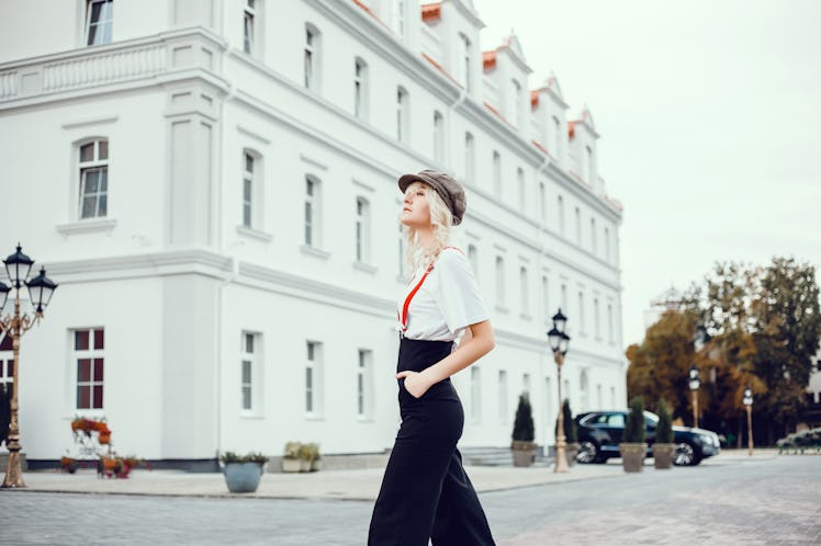 A fashionable woman stands in the streets of London near a white building.