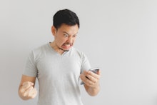Angry Asian man in grey t-shirt get mad on the smartphone.