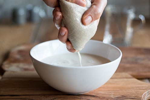 Preparation of nut milk - straining the milk through a milk bag