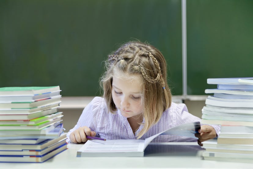Model Released - Schoolgirl, 7 years, reading a book whilst sitting between two stacks of books, in ...