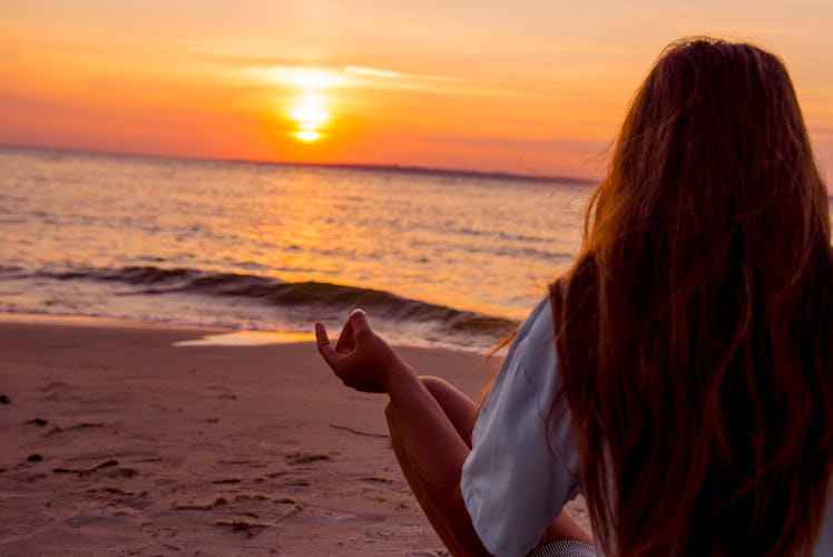 Girl is engaged in yoga on the beach. girl is meditating. Girl with long hair sitting on the beach. ...