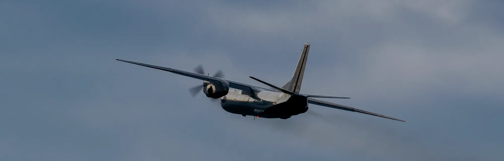 Turboprop cargo plane is rolling after takeoff on stormy sunset
