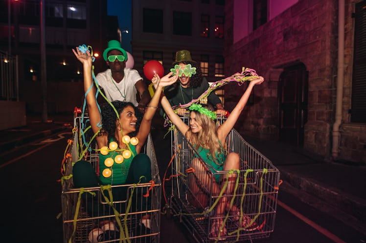 Four friends have fun on St. Patrick's Day in shopping carts and throw streamers in the air.