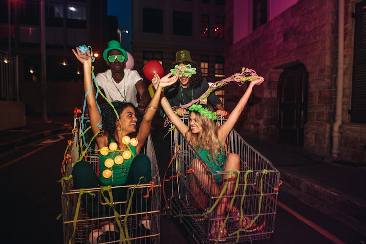 Four friends have fun on St. Patrick's Day in shopping carts and throw streamers in the air.