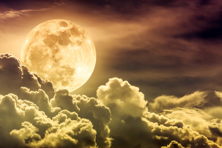 Attractive photo of gold background nighttime sky with clouds and bright full moon with shiny. Night...