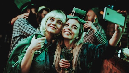 Two girls smile and snap a selfie at a bar on St. Patrick's Day.
