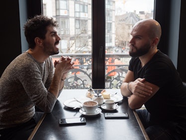 Two young guys friends with beards arguing in a coffee shop