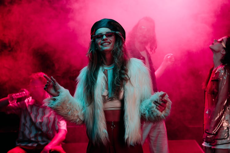cheerful girl dancing in nightclub with pink smoke