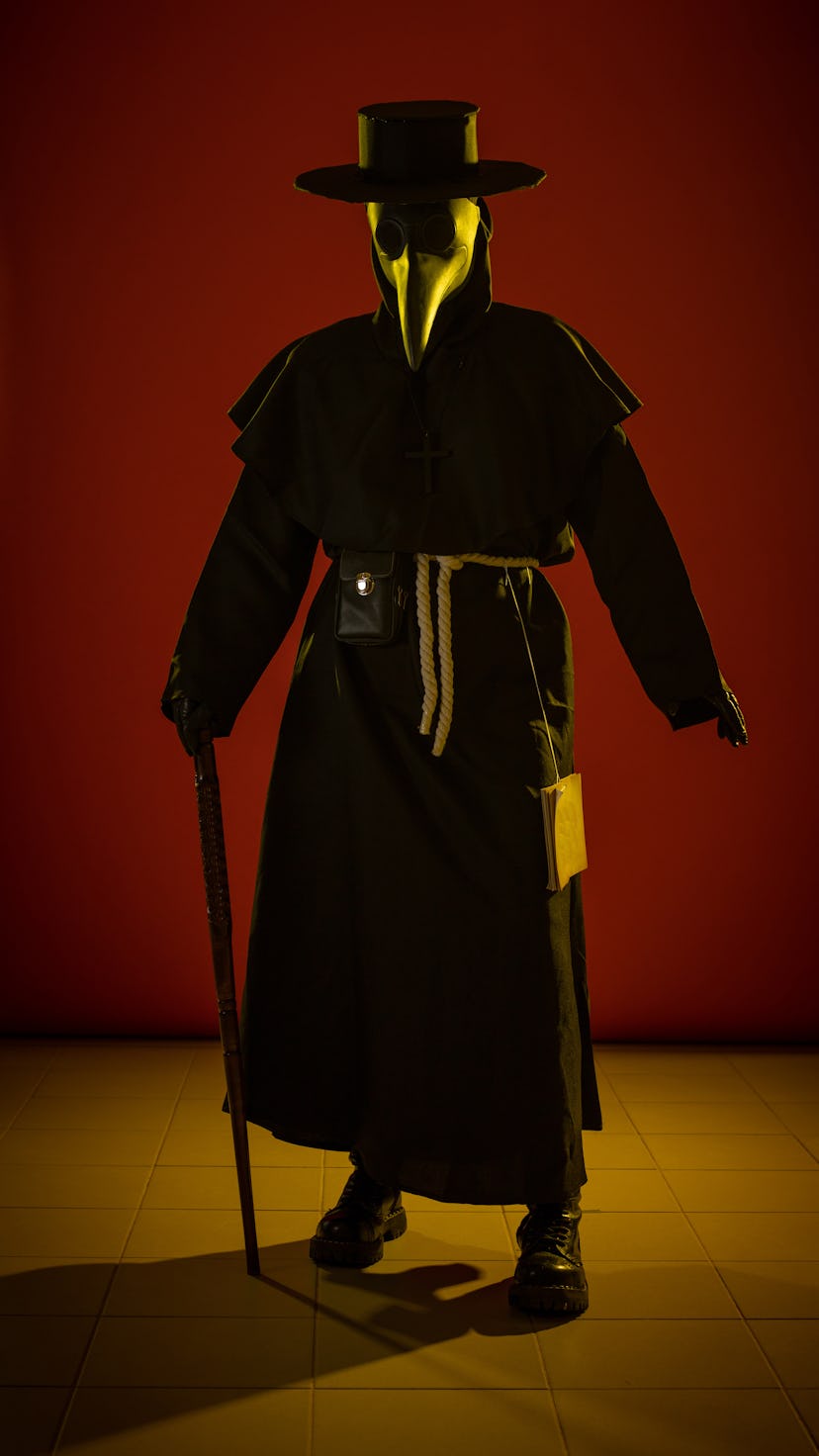 Actress woman in mask and costume of fictional fantasy character posing on red background