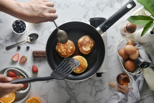 Flip the pancakes with a spatula. Concept of Cooking ingredients and method on white marble backgrou...