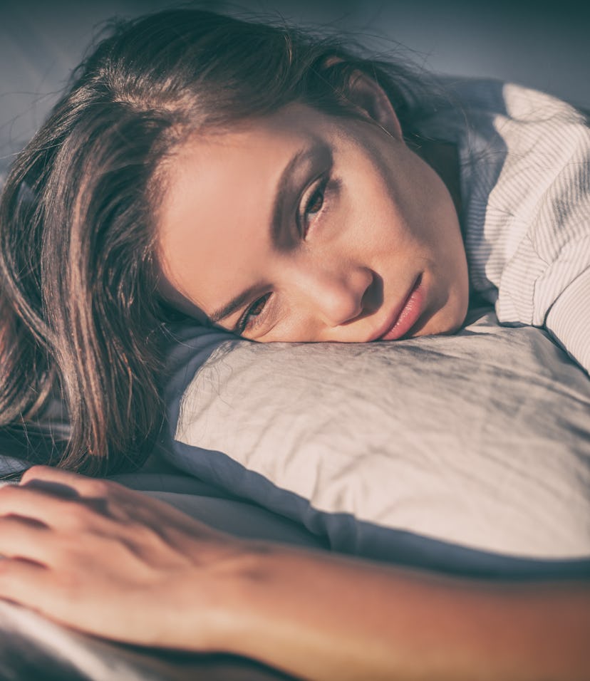 Tired woman lying in bed can't sleep late at night with insomnia. Asian girl with funny face sick or...