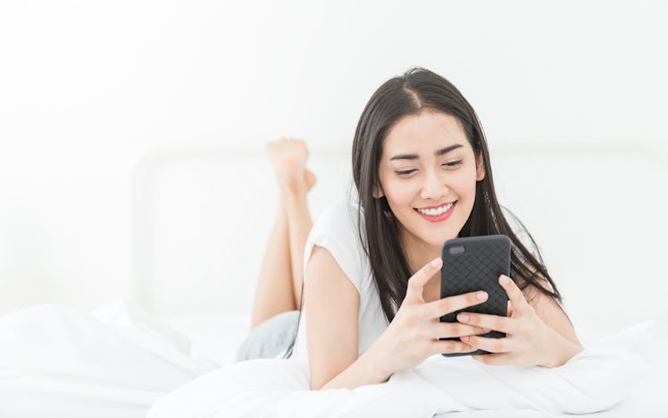 Asian woman with attractive smile use tablet smartphone on white bed, Portrait young beauty sexy gir...